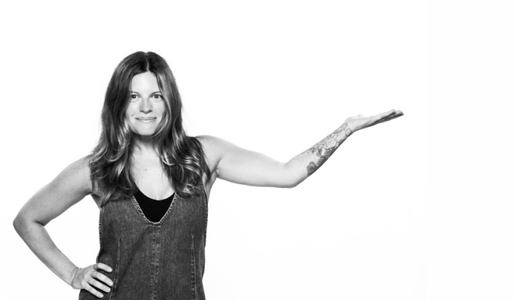A black-and-white portrait of Vanessa Airey with one hand extended in a presenting gesture.